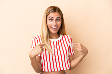 Blonde Uruguayan girl isolated on beige background with surprise facial expression