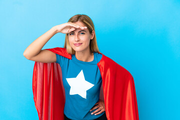 Blonde woman over isolated background in superhero costume and showing something