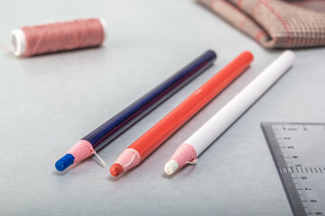 Multi-colored tailor's markers and sewing accessories lie on the table