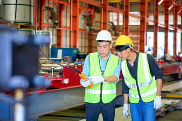 Two asian engineer working with lift remote control in metal sheet factory