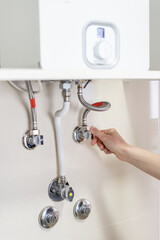 Person's hand adjusting boiler for getting hot water
