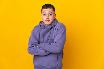 Young caucasian man isolated on yellow background making doubts gesture while lifting the shoulders