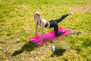 Fototapeta premium Blonde woman in lotus position, practicing yoga on sunny day in nature. Sit in yoga poses, practice meditation. 