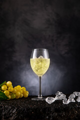 Weißwein eiskalt im Glas mit Trauben und Eiswürfel