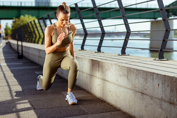 Young woman in sportswear stretching on a river promenade