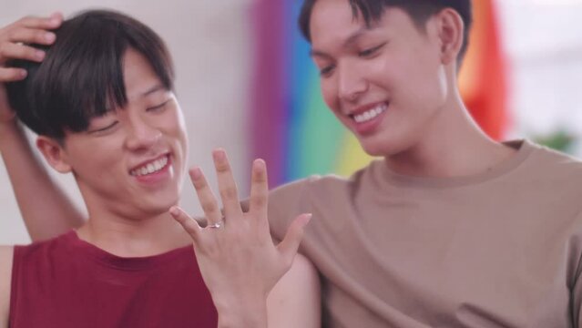 Happy gay Asian couple showing off their wedding ring.