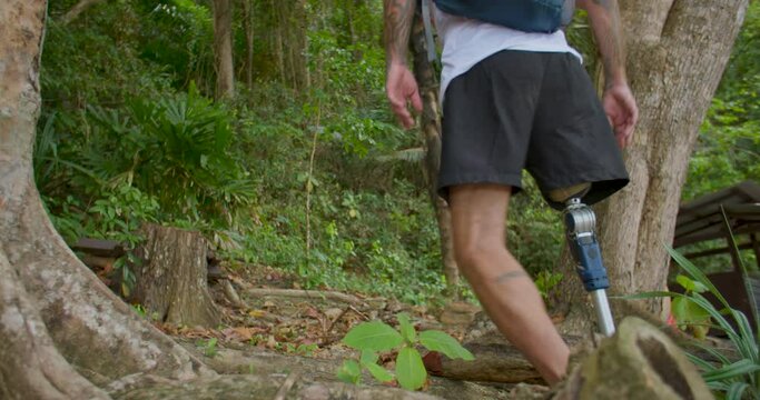 Male hiker with artificial bionic legs prosthesis enjoying the mountains hiking. Disabled man with backpack walks through forest. Active lifestyle for people with disabilities. outdoor activities.