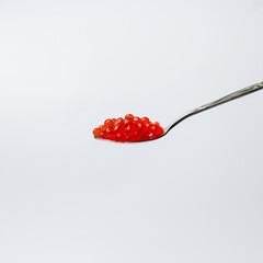 Red caviar on silver spoon isolated on white background close-up. Top view.  Red caviar salmon on...