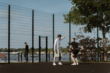 two guys play basketball outdoors on the court