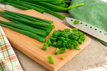 Green onion feathers are cut on a cutting board. Vegetable in the form of green onions. Cooking green onions.