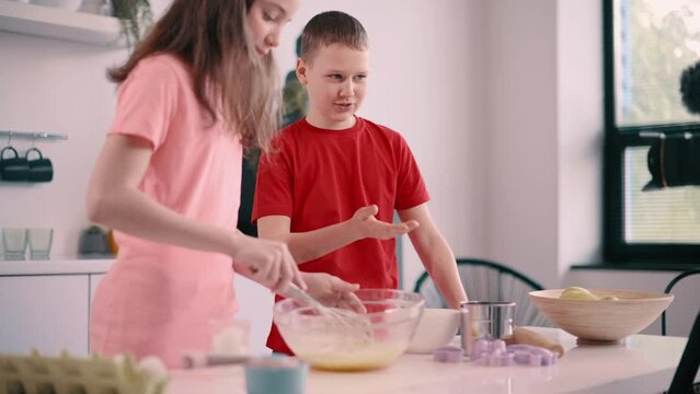 Boy and girl recording culinary blog at home. Children make dough together.