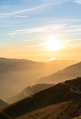 Mountain chain and beautiful sunset, road in hills under evening sky