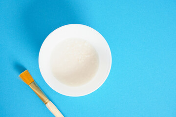rice water and cosmetic brush on blue background