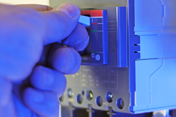 The engineer's hand turns on the automatic current switch in close-up.