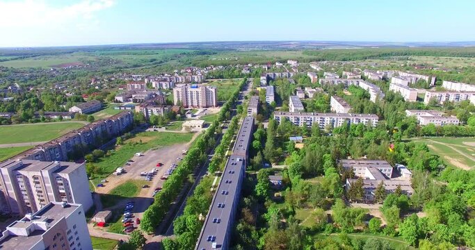 Cityscape with numerous blocks of flats. Picture of beautiful green town with rural outskirts. Aerial view.