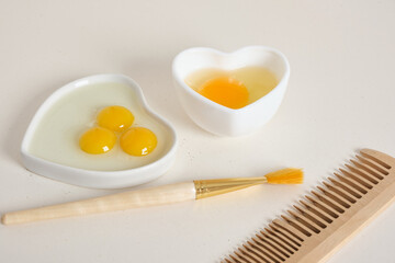 egg-based face, hair and body mask, DIY natural cosmetics concept,comb, brush and egg in a heart-shaped bowl