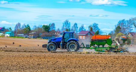 Mozhayskoe, Russia, 06 May 2022, A tractor with a seeder in the field sows grains of wheat or oats to grow grain products.