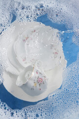 Beautiful dishes in water with foam, washing dishes, aesthetics