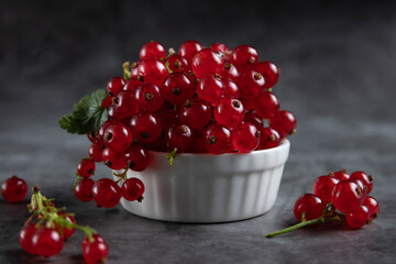 Red current in a small cup, standing on a wooden table