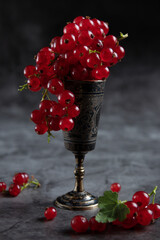 Fototapeta na wymiar Red current in an iron glass, standing on a wooden table, branches of fresh berries, rustic style