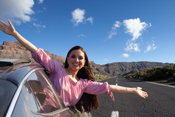 Happy woman smiling and holding hands outside open window car against road and mountain background. People lifestyle relaxing as traveler on road trip in holiday vacation, travel concept