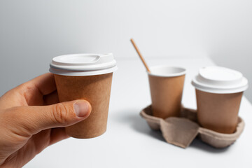 Close-up of male hand holding paper cup. Coffee takeaway concept on white.