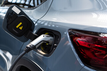 Fototapeta premium Close up of electric car with a connected charging cable 