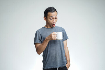 Surprised face of Asian man drinks a cup of coffee isolated on white background