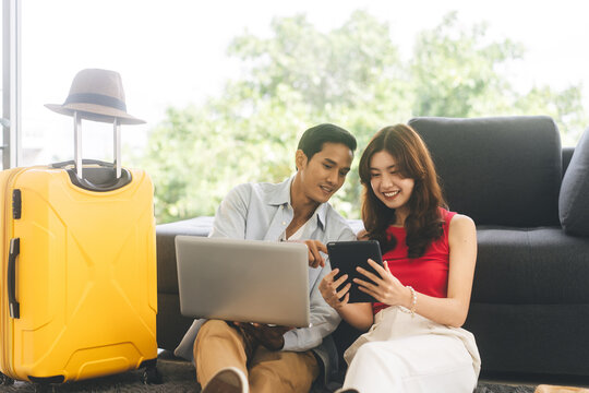 Happy smile young adult southeast asian couple using laptop for getting ready for holidays travel trip