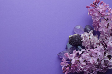 Beautiful  lilac flowers and semi-precious stones amethyst lie on a purple background. Copy space.
