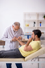 Young male patient visiting old male doctor chiropractor