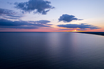 Fototapeta na wymiar Sunrise over the sea. Early morning on the beach by the ocean. Red rising sun.