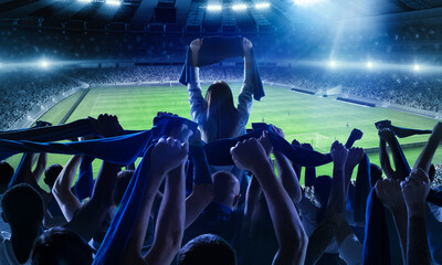 Back view of football, soccer fans cheering their team with scarfs at crowded stadium at evening time. Concept of sport, support, competition. Out of focus effect - obrazy, fototapety, plakaty
