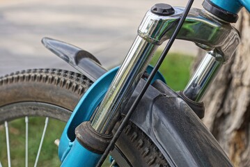part of a sports bike from a metal fork spring on a black wheel with a plastic fender on the street