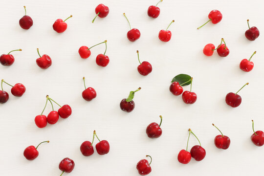 Top view image of red sweet cherry over wooden white background
