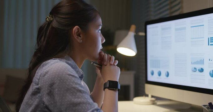 Young asia woman talent workforce people happy work hard late night busy sit at home office desk read sale plan report data online on desktop PC in hybrid workspace reskill upskill class for worker.