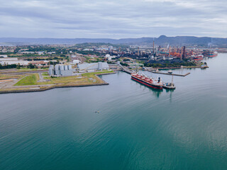 Aerial drone view of Port Kembla, in the Illawarra Region of NSW, showing the seaport, industrial complex and small harbour foreshore   