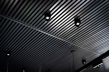 Bottom view of lath ceiling with spot lights. Abstract modern architecture or interior background in black and white with geometric structure.