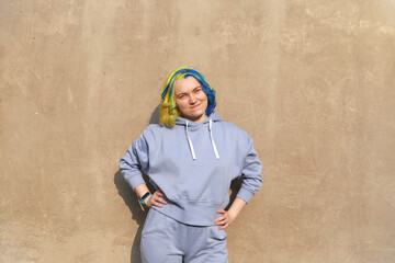 Beautiful woman with colored hair on concrete wall smiling 