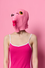 Woman in a fish costume for Halloween poses against a pink background in a crazy scary costume with a pink silicone mask on her head