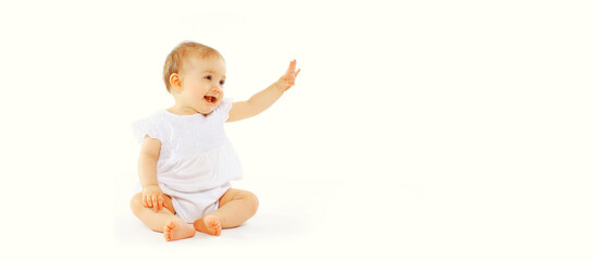 Cute baby looking up sitting on the floor greeting waving his hand on white background, banner...