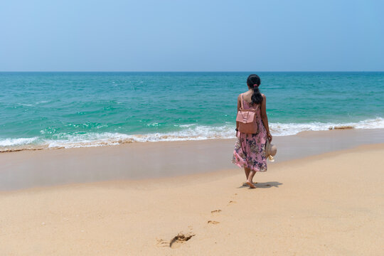 Picture of a woman walking on a beach at golden sand beach, Trivandrum, Kerala. Poovar island, Estuary beach, Kovalam resort. Turquoise sea, solitude, loneliness, happy, sad, travel, tourist concept.