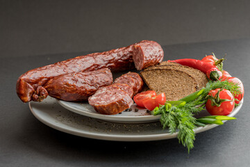 Sliced sausage, bread and vegetables with spices on plate