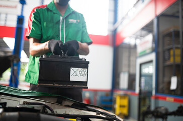 Fototapeta premium mechanic changing car battery An engineer is replacing a car battery because the car battery is dead. concept car care