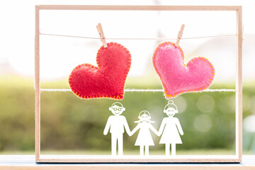 Family with paper cut and red and pink heart put on the wood on the sunlight in the public park, Saving money for buy health insurance to the loved ones concept.