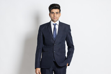 Portrait of a confident young indian man wearing suit standing isolated on white studio background.