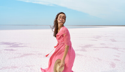 Motion portrait happy laughing woman in pink dress playful having fun on desert beach of salt pink...