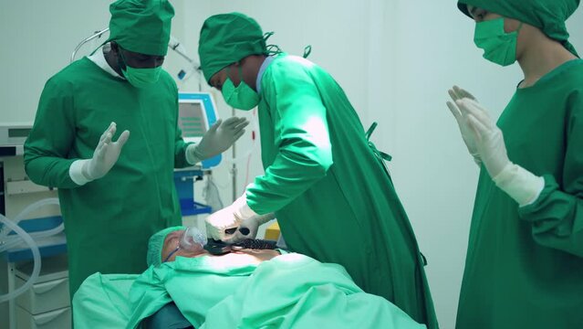 Professional Doctor And Team Working In The Operating Room At Hospital. Using Defibrillators To Shock The Patient Heart In ICU. Medical Respiratory And Life Support Systems. Emergency Medical 