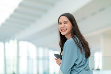 asian smiling cheerful female digital nomad hand hold tablet device look at camera portrait shot,happiness smiling asia woman standing in office college corridor with positive smiling attitude