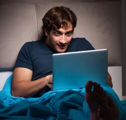 Man working on laptop at night in bed